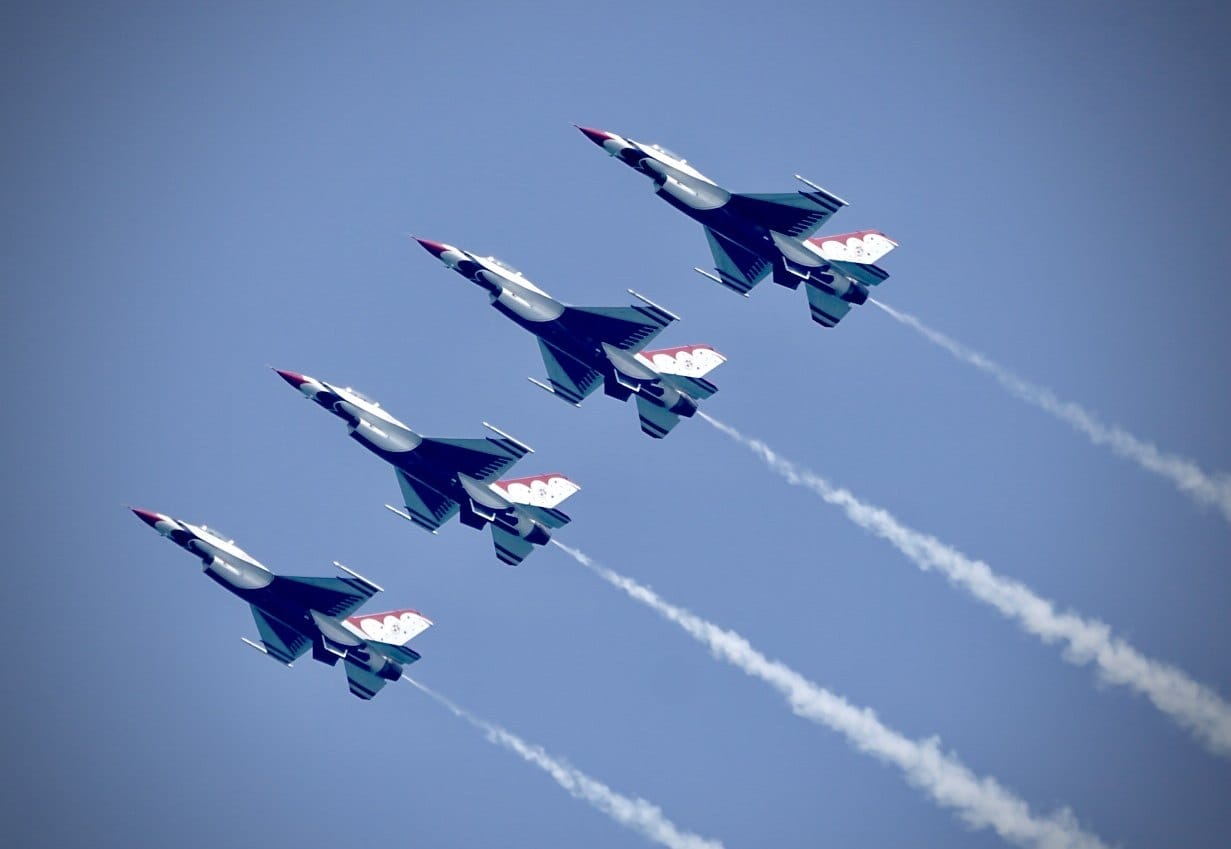 Five jets climb in a sweeping formation beneath a blue sky. — by Ed Shpritz