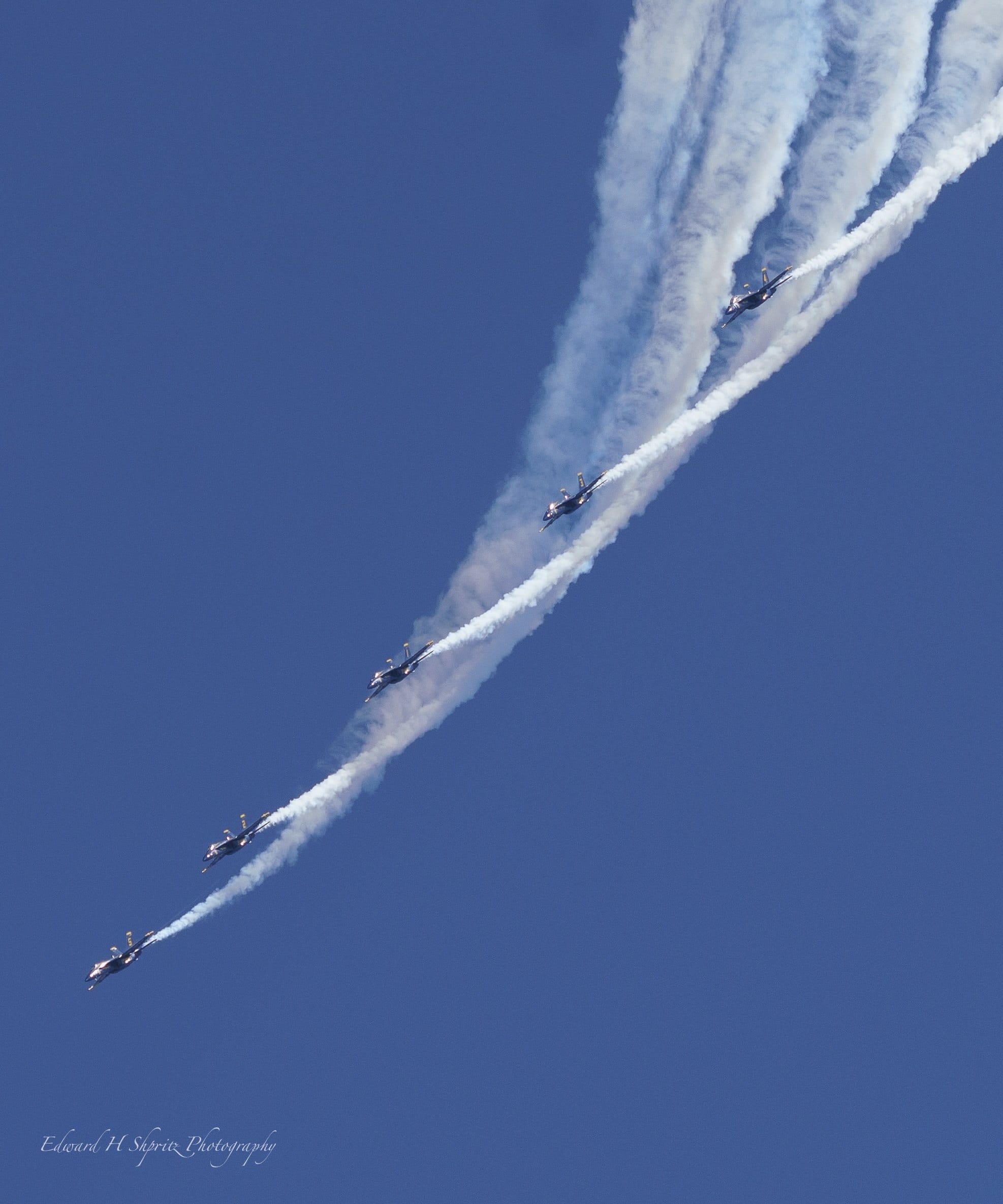 A line of jets sweeps diagonally through a veil of smoke. — by Ed Shpritz