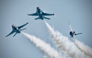 Three jets fan outward in a smoky sky. — by Ed Shpritz