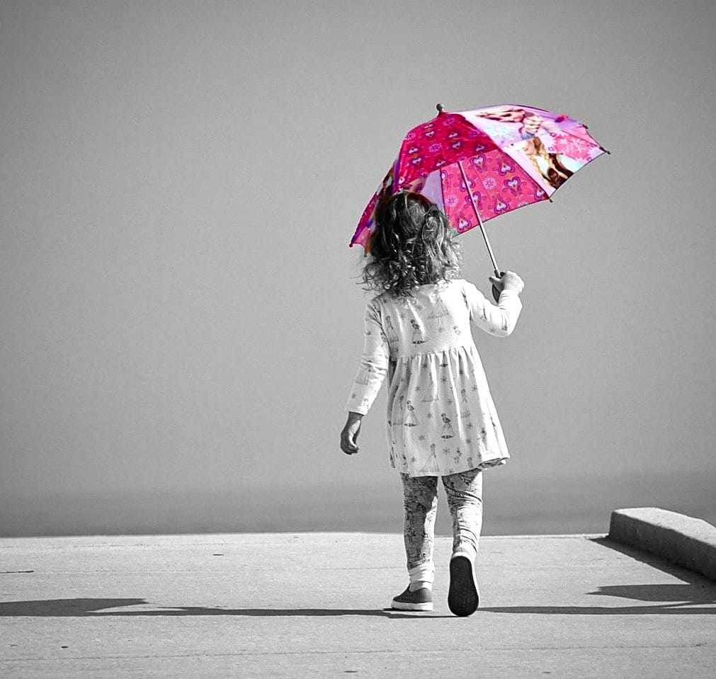 Young girl walking beneath a vivid umbrella