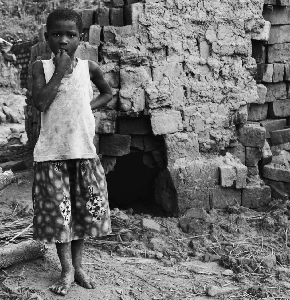 A child stands in the doorway of a stone building. — by Ed Shpritz