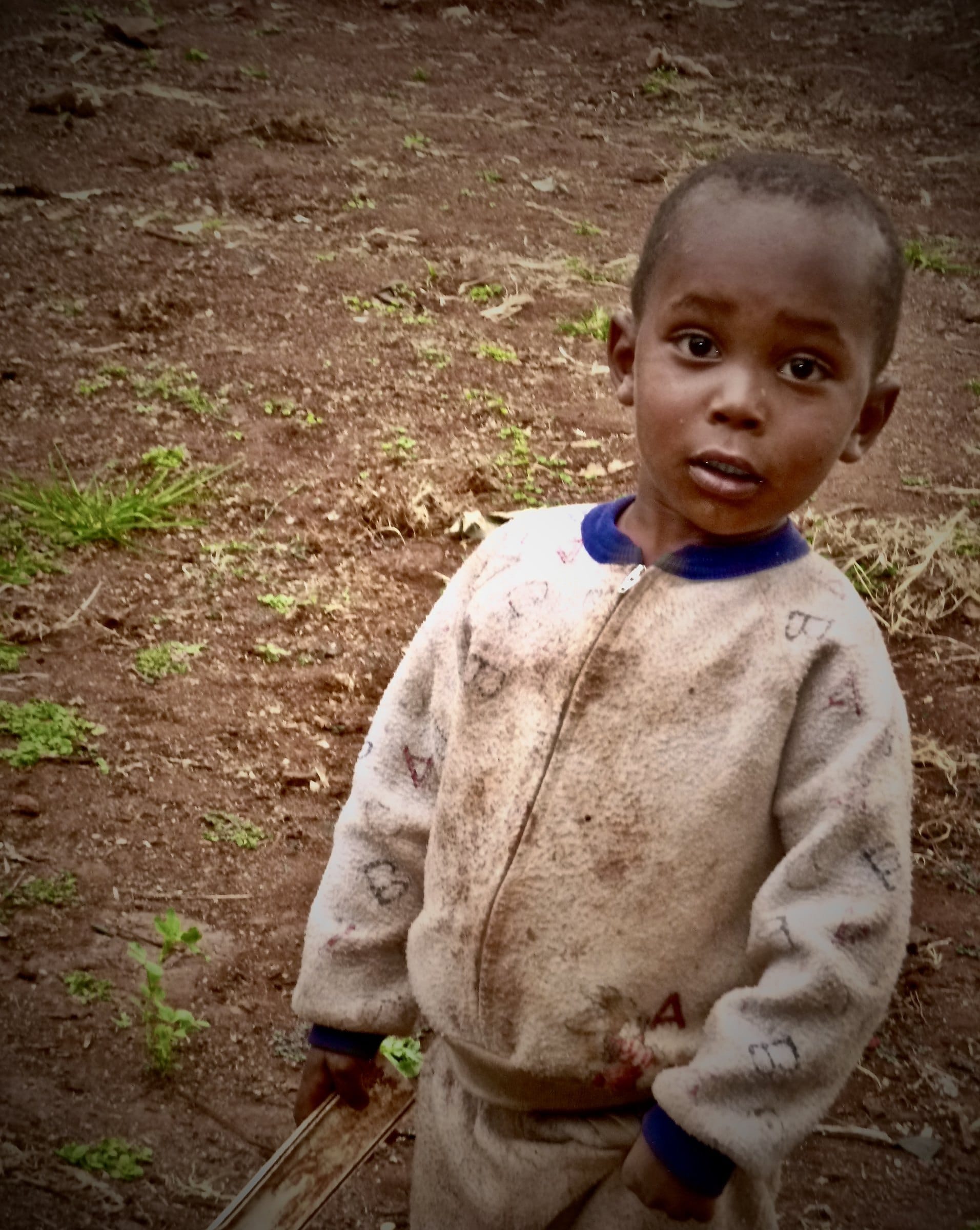 A child looks toward the camera outdoors. — by Ed Shpritz