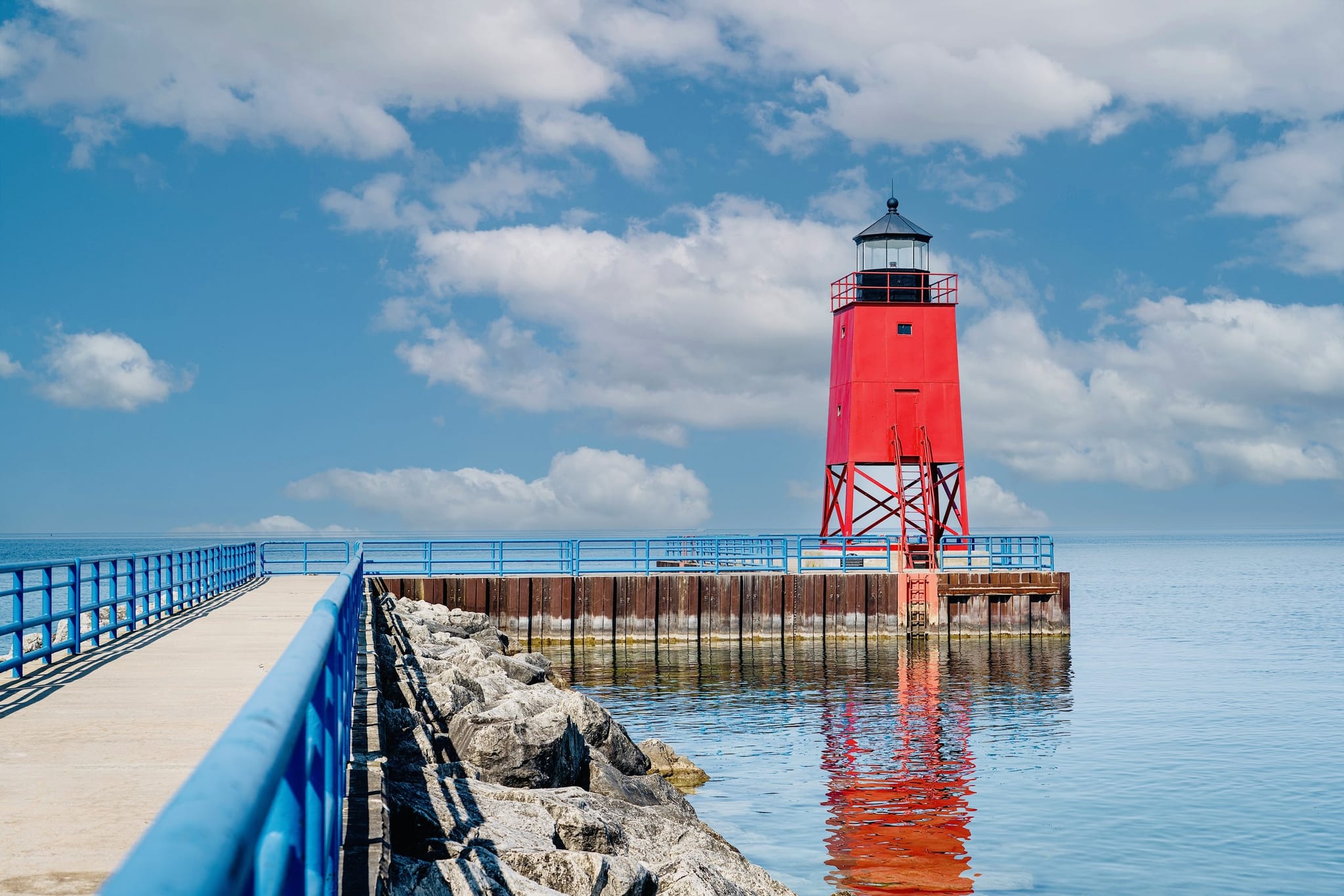 The red Charlevoix South Pier Light reflected in calm blue water