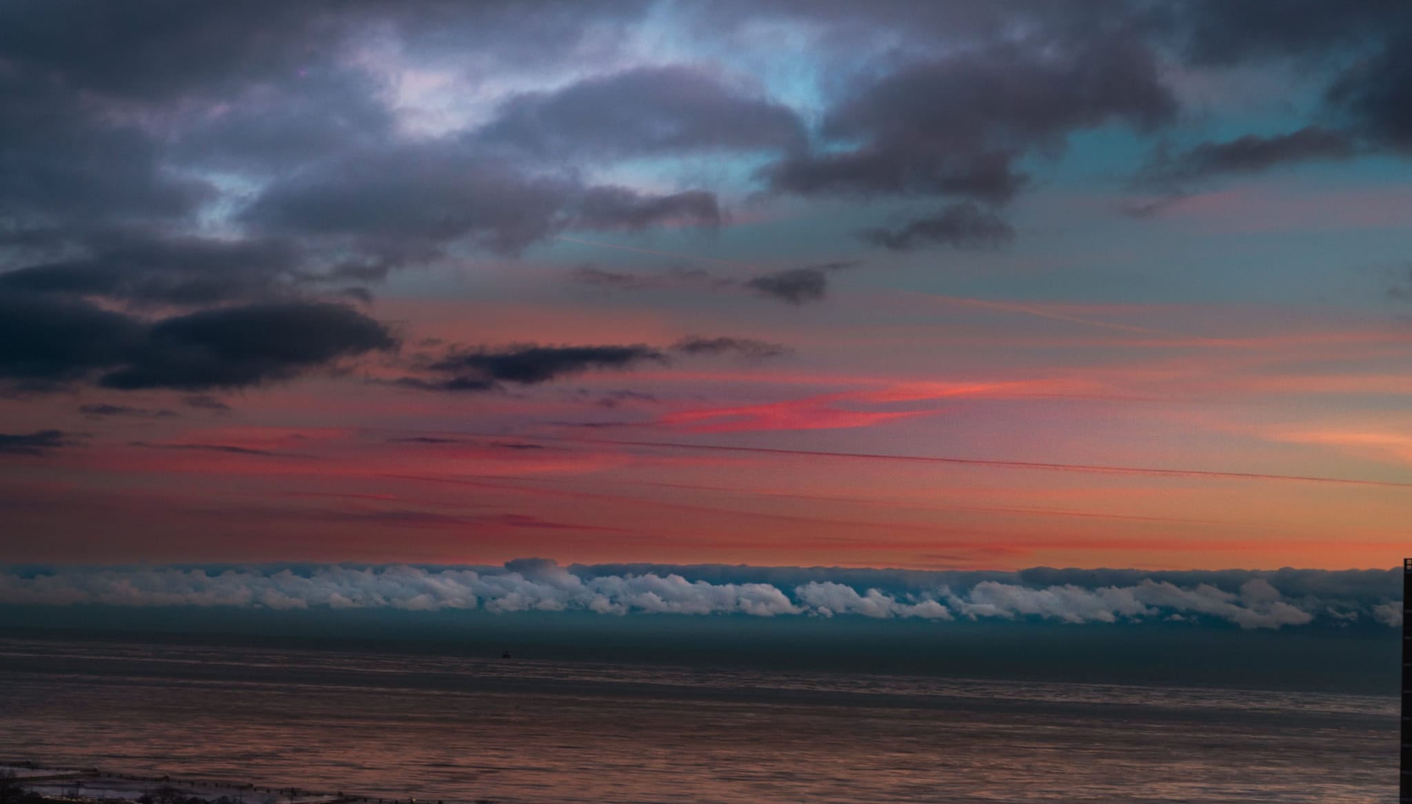 A layered pink and blue sunset above a long cloud bank over Lake Michigan