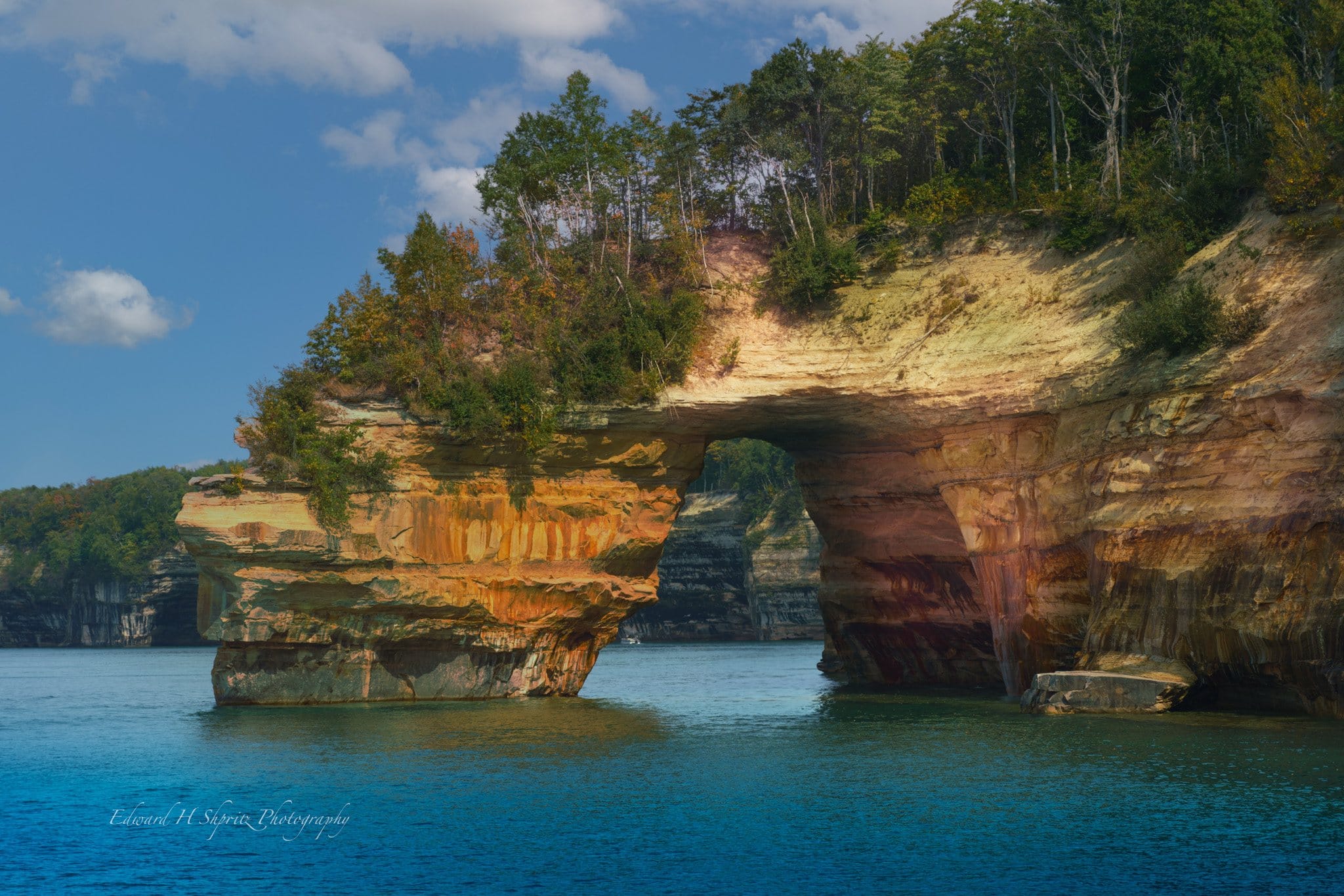 A sandstone arch rising from the blue water at Pictured Rocks