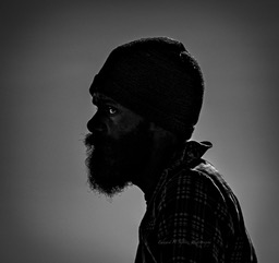 A black and white profile portrait of a bearded man