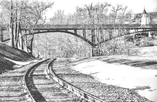 Railroad tracks curving away into snow, black and white