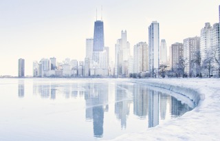 The Chicago skyline reflected in icy lake water, soft pastel